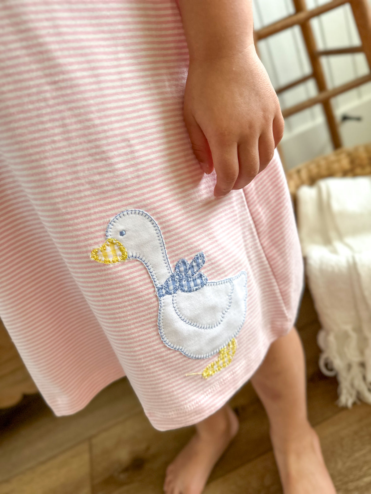 Pink dress with a duck applique on a wooden floor.