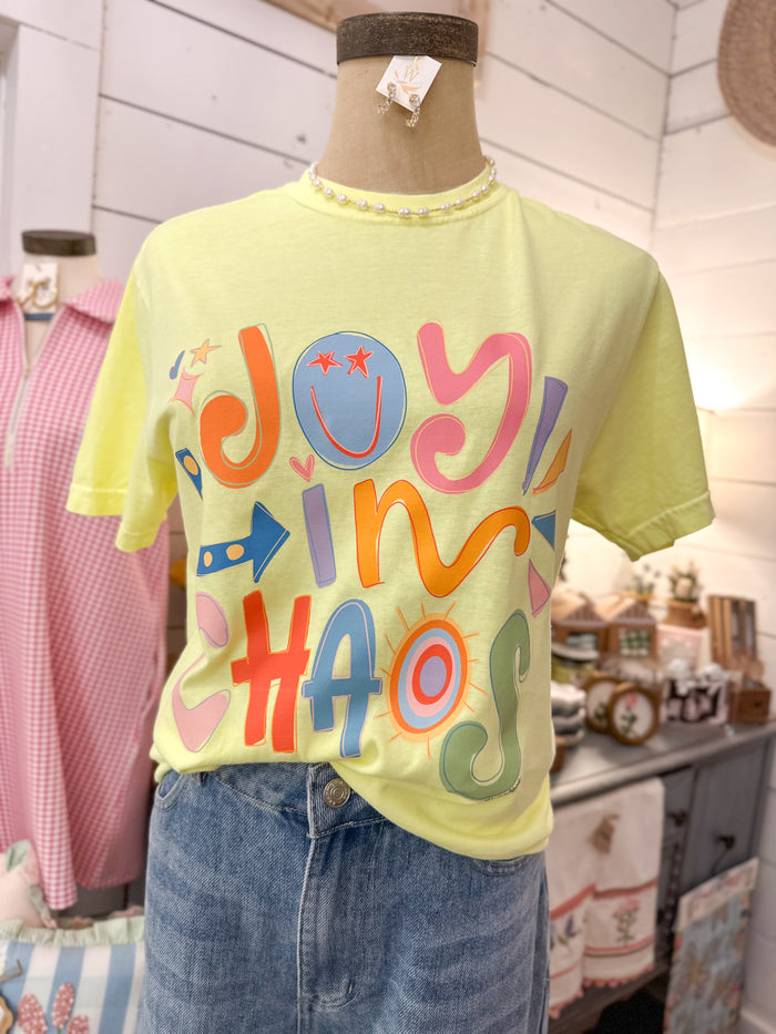 Yellow t-shirt with colorful text joy in chaos on a mannequin in a store setting.