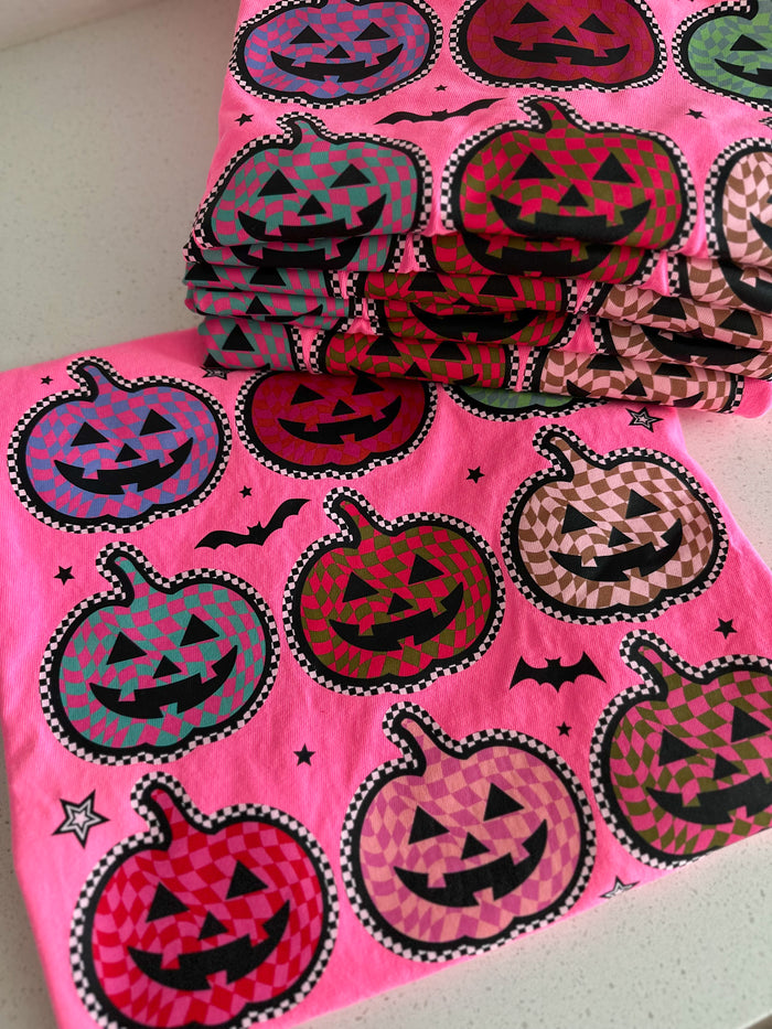 Pink tee with Halloween-themed jack-o'-lantern patterns on a white background