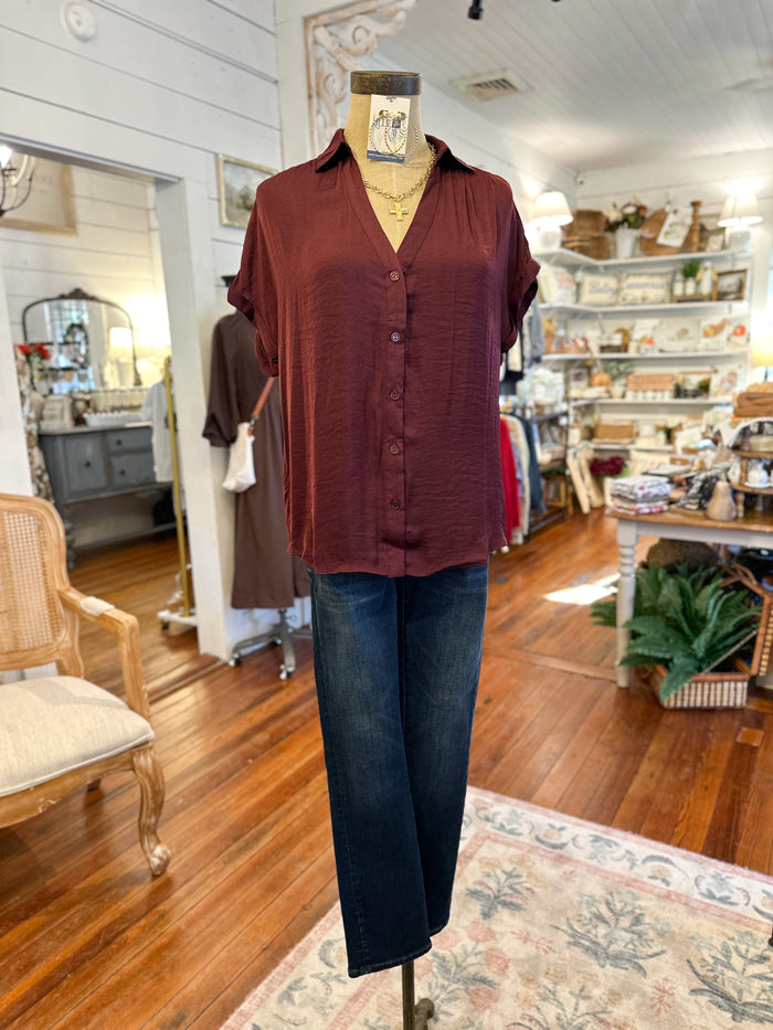 Mannequin wearing a burgundy shirt and blue jeans in a store setting