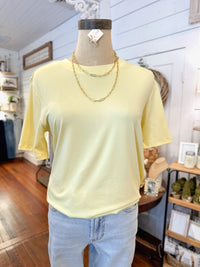 Mannequin wearing a light yellow t-shirt and blue jeans in a store setting.