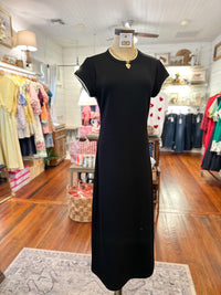 Black dress on a mannequin in a store with wooden floors and clothing racks.