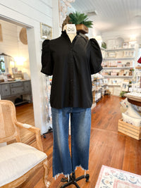 Mannequin wearing a black blouse and blue jeans in a store setting