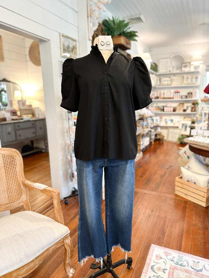 Mannequin wearing a black blouse and blue jeans in a store setting