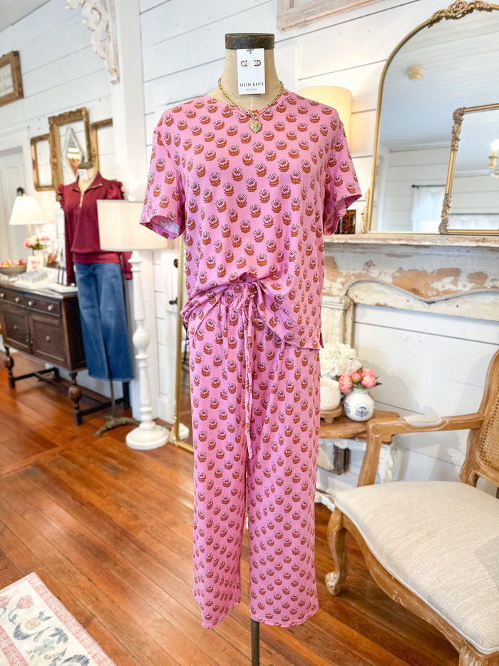 Pink floral block print pajama set in a room with wooden floor and furniture.