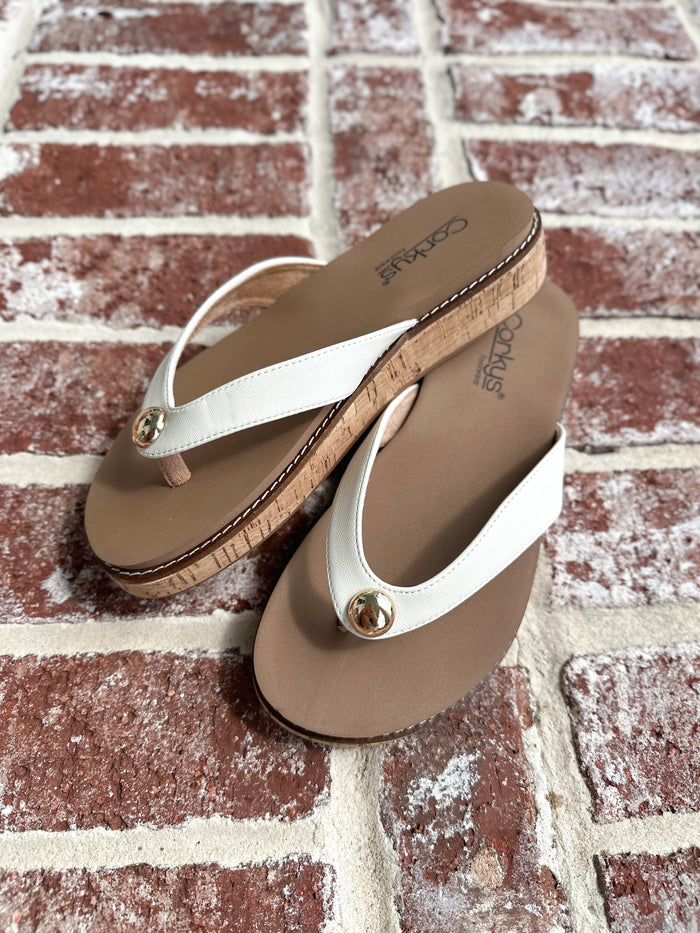 Pair of tan and white sandals on a brick surface