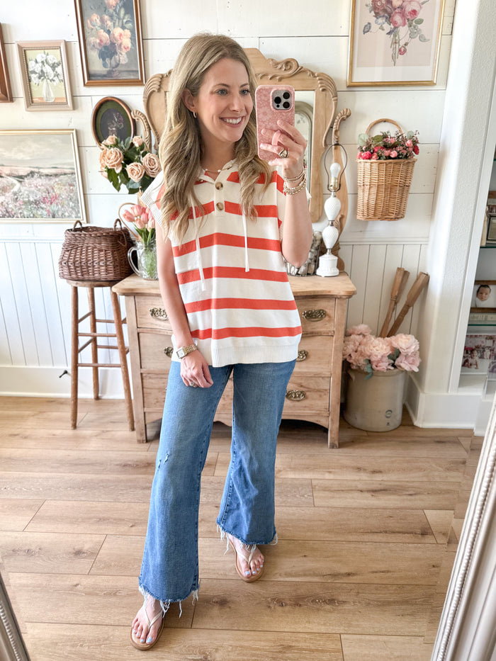 Woman taking a mirror selfie wearing a striped shirt and jeans in a home setting.