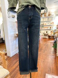 Person wearing dark blue jeans standing in a room with wooden floors. dear john blaire jean 