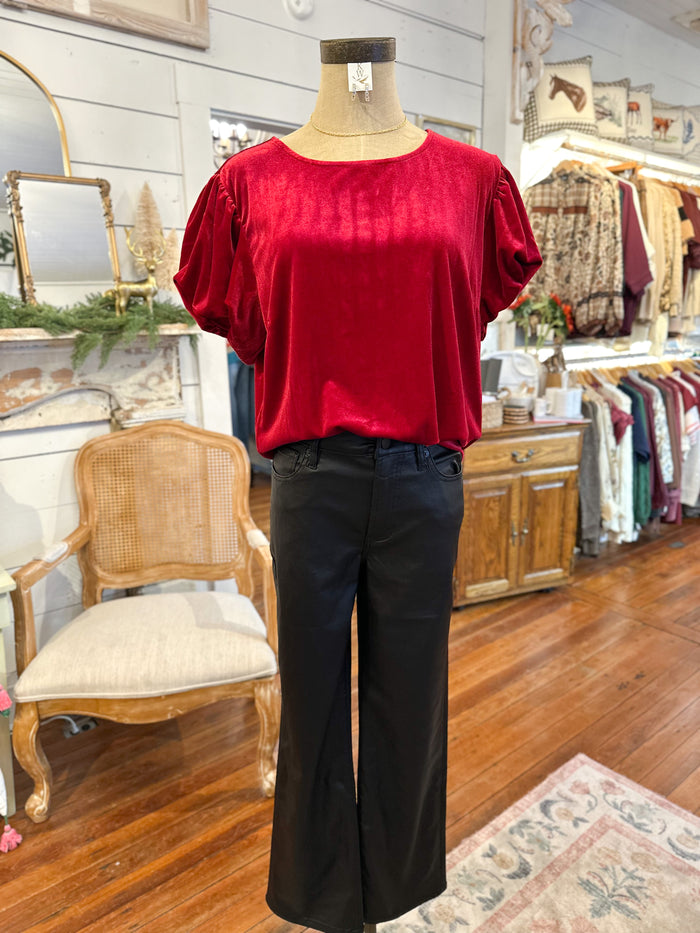 Mannequin wearing a red top and black pants in a store setting with furniture and decor.