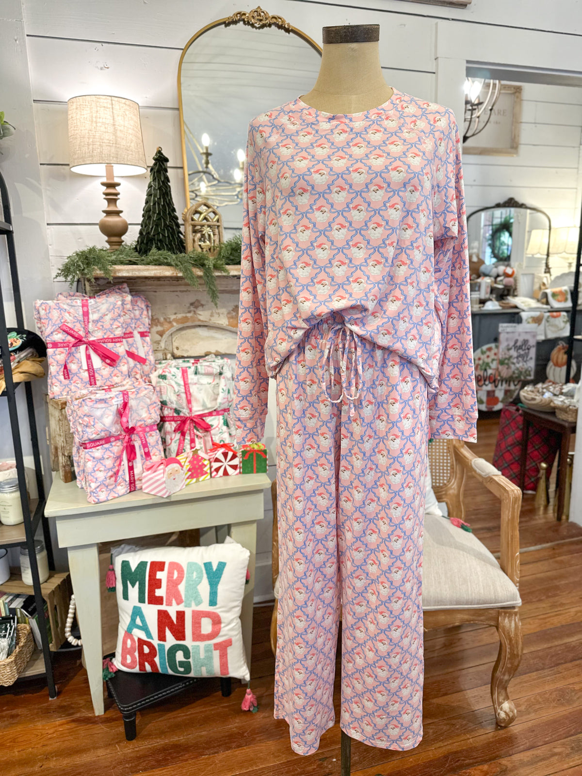 Patterned pajama set on a mannequin with decorative pillows and Christmas decor in the background. pink santa 