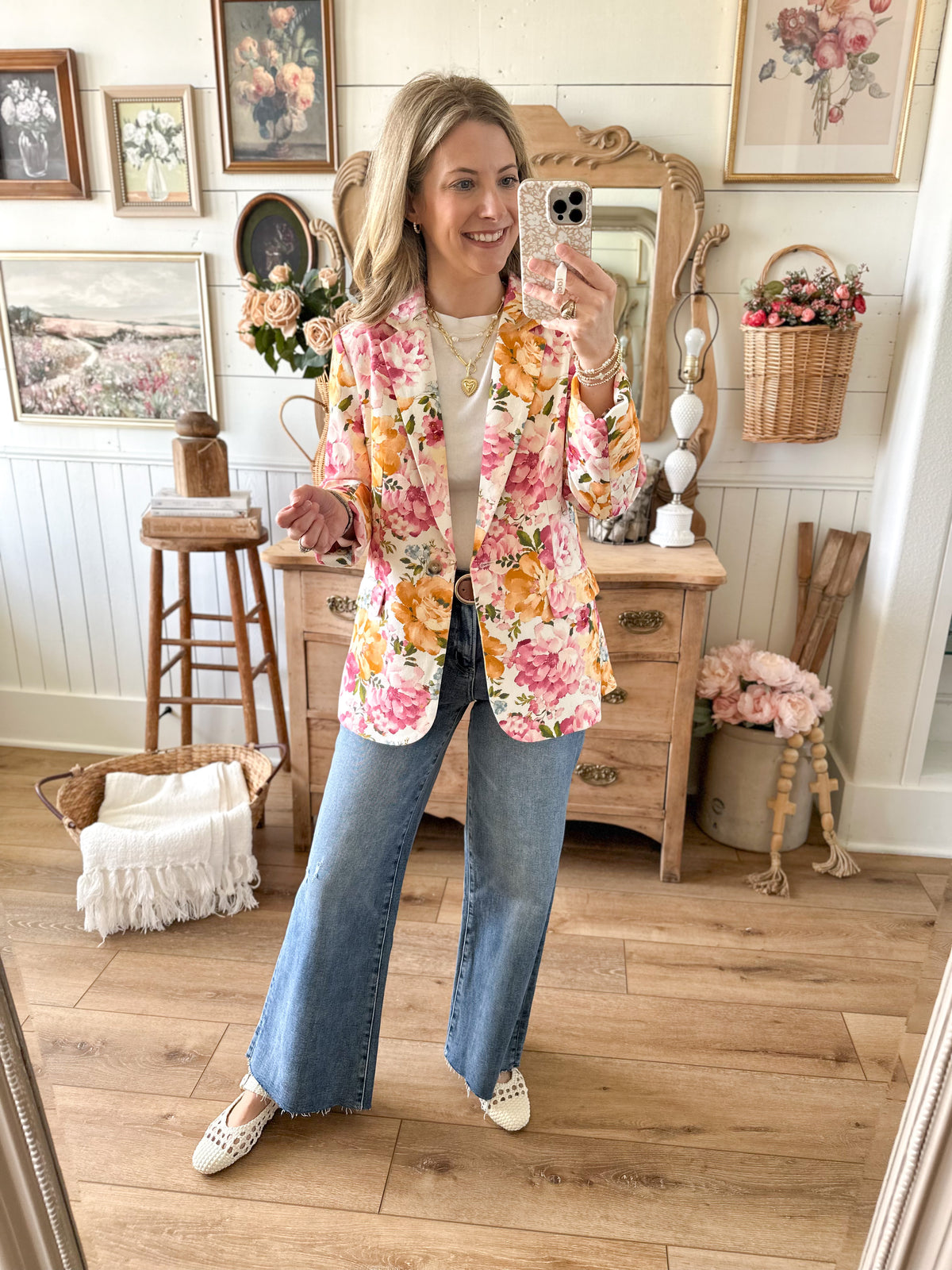 Woman taking a mirror selfie wearing a floral jacket in a home setting.