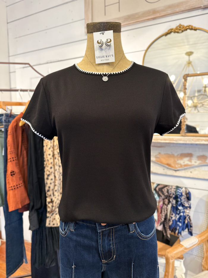 Black short-sleeve top with leopard print sleeves on a mannequin in a store setting.