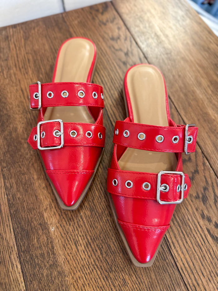 Red pointed-toe shoes with buckles on a wooden surface