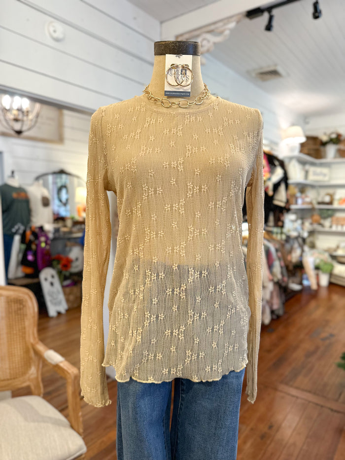 Beige long-sleeve top with floral pattern on a mannequin in a store setting
