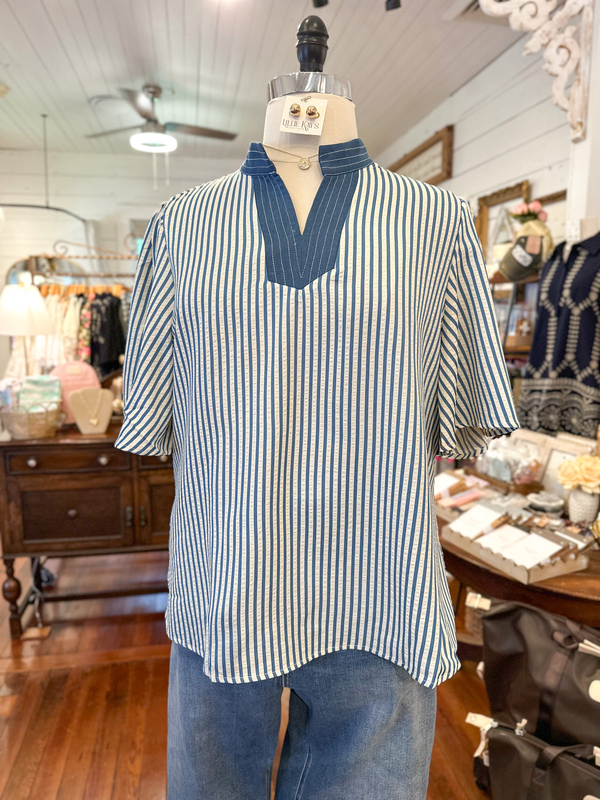 Mannequin wearing a blue and white striped shirt in a store setting