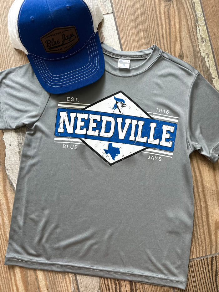 Gray t-shirt with 'NEEDVILLE' design and blue cap on wooden surface