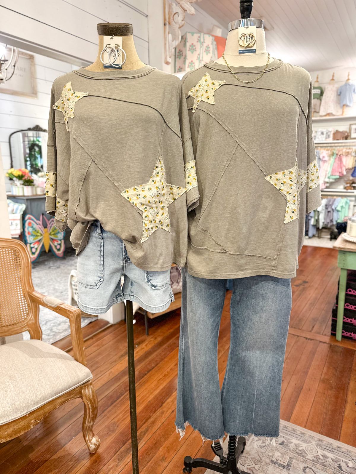 Two mannequins wearing olive green sweatshirts with star patterns in a store setting.