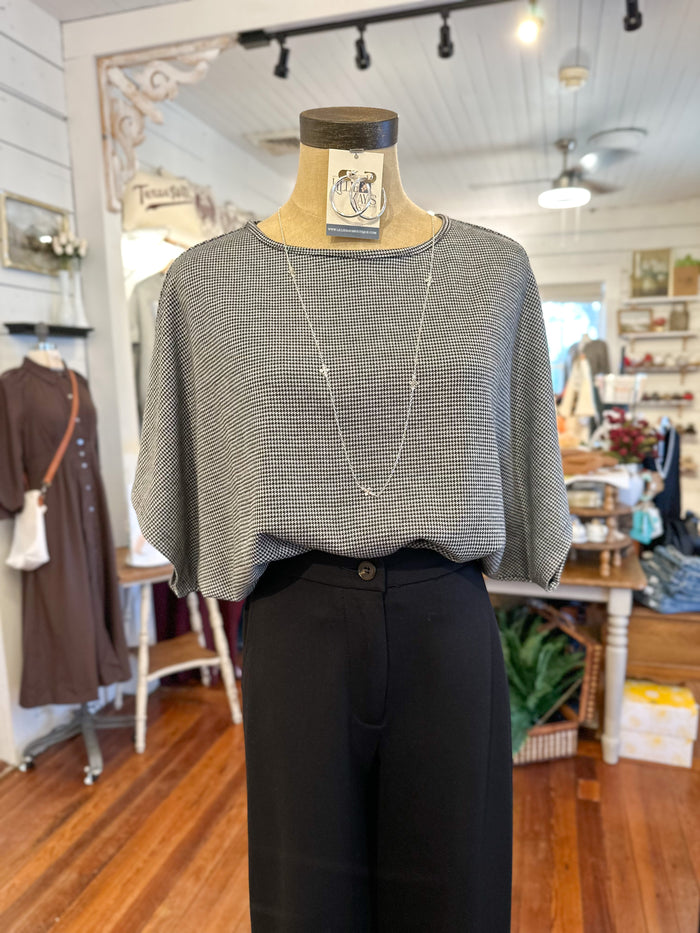 Mannequin wearing a black and white  checkered top and black pants in a store setting