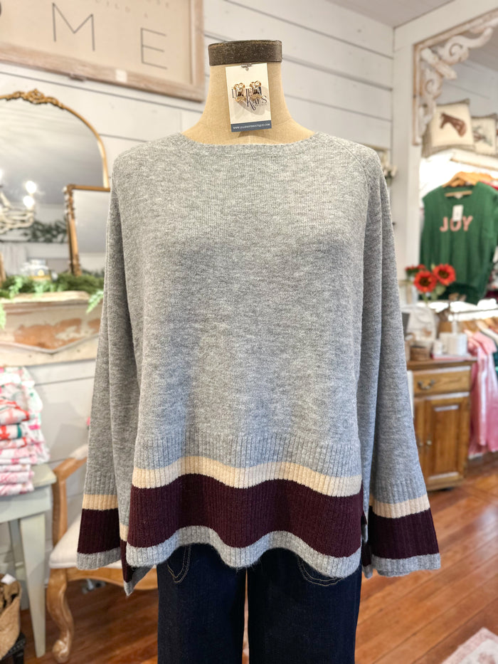 Gray sweater with colorful hem on a mannequin in a store setting