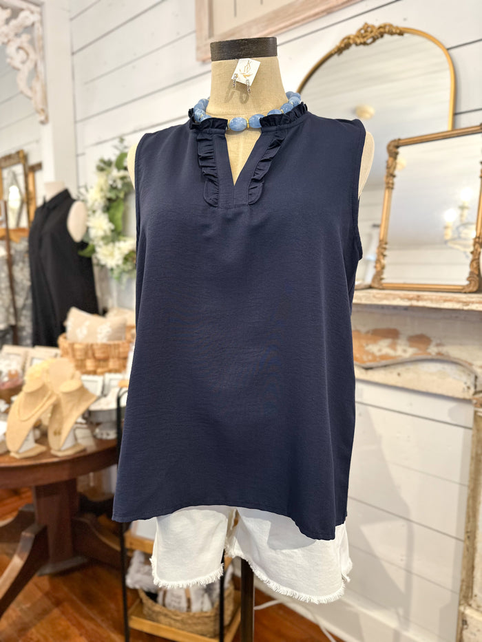 Navy sleeveless top with ruffled neckline on a mannequin in a store setting.