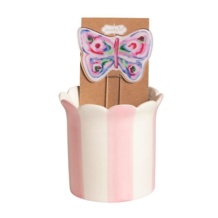 Decorative vase with a colorful butterfly design on a cardboard stand against a white background pink and white stripe plant holder 