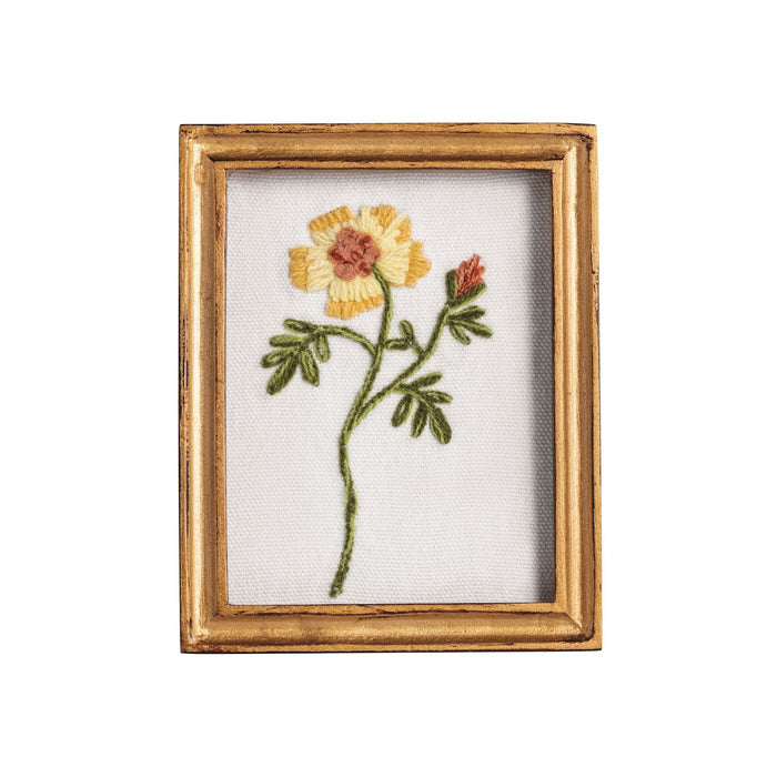 Embroidered flower on fabric in a gold frame against a white background
