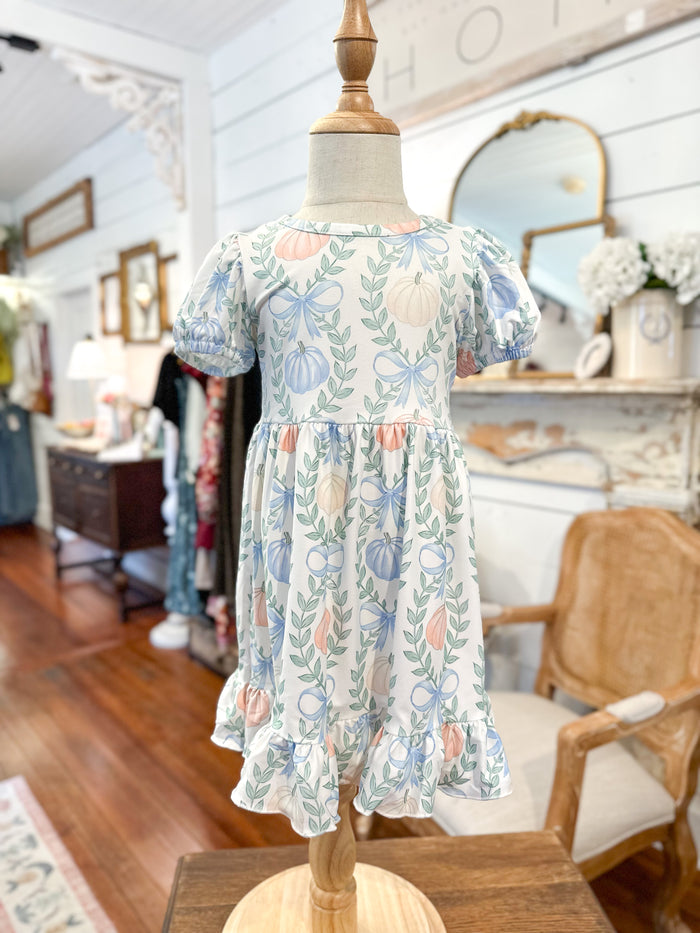 Floral dress on a mannequin in a home setting with furniture and decor. pastel pumpkin dress for kids 