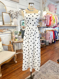 White dress with black polka dots on a mannequin in a store setting.