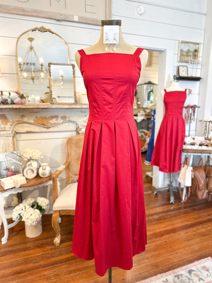 Red dress on a mannequin in a room with wooden floor and decorative items.