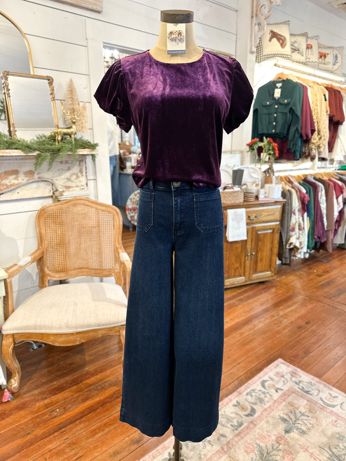 Mannequin wearing a purple top and blue jeans in a store setting