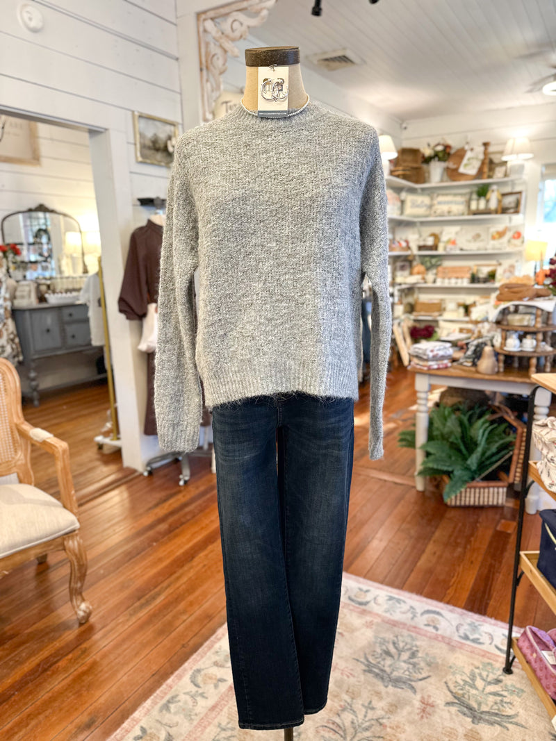 Mannequin wearing a gray sweater and dark jeans in a store setting