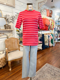Mannequin wearing a pink striped shirt and light blue jeans in a store setting.