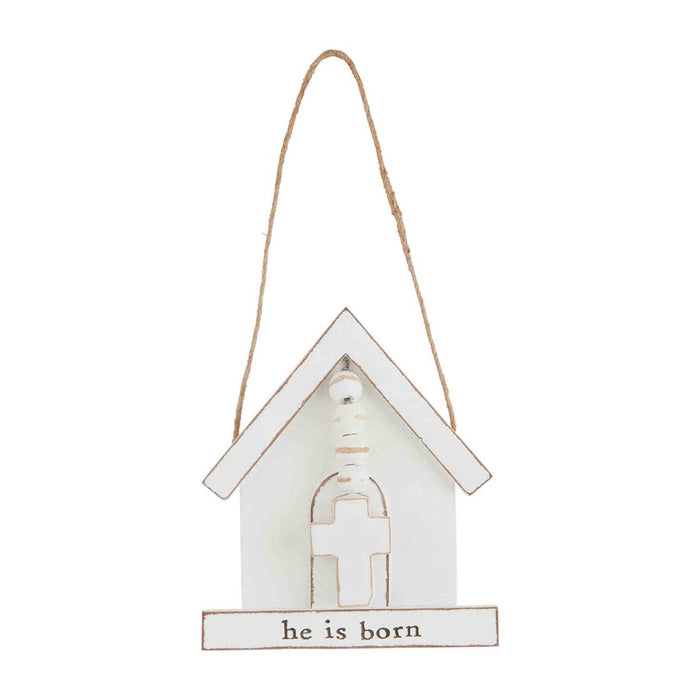 White wooden house-shaped sign with 'he is born' text on a white background