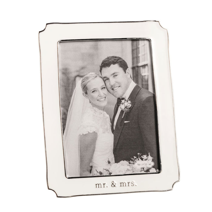 Silver and white enamel photo frame with 'Mr. & Mrs.' engraving, containing a wedding photo of a couple.