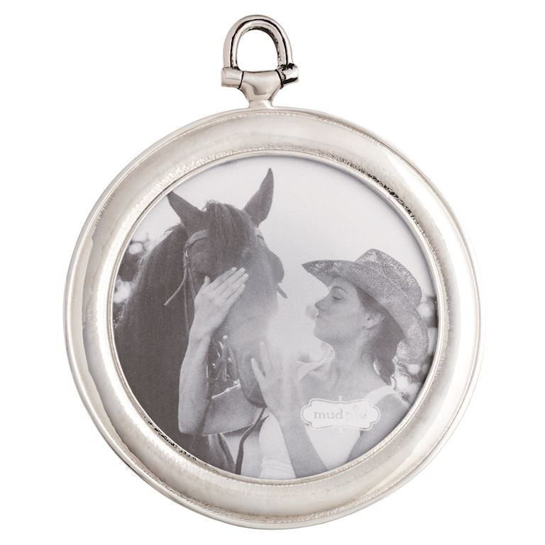 Round silver photo frame with a black and white photo of a woman and horse inside.