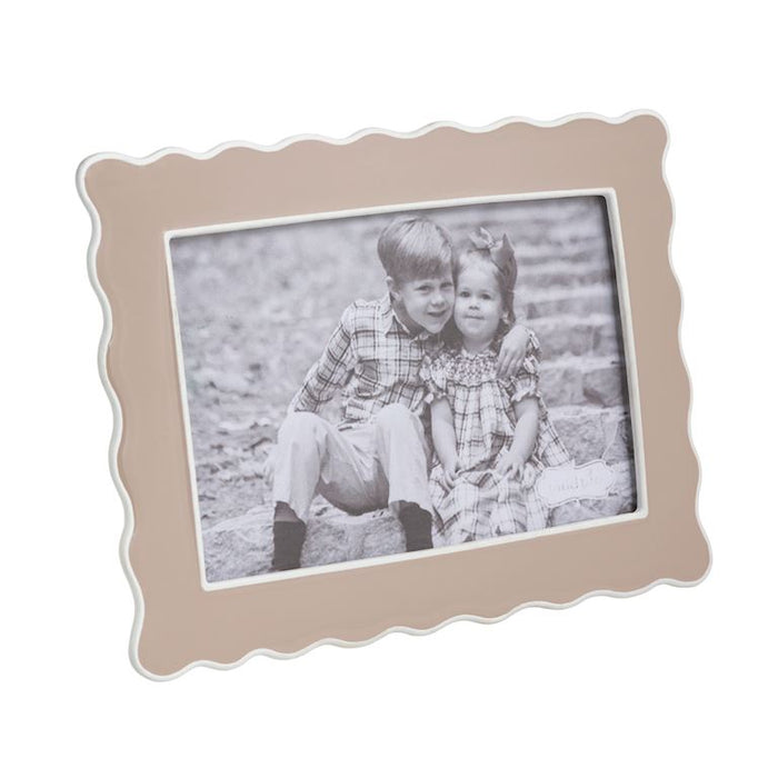 Beige scalloped photo frame with a black and white photo of two children on a stone path.