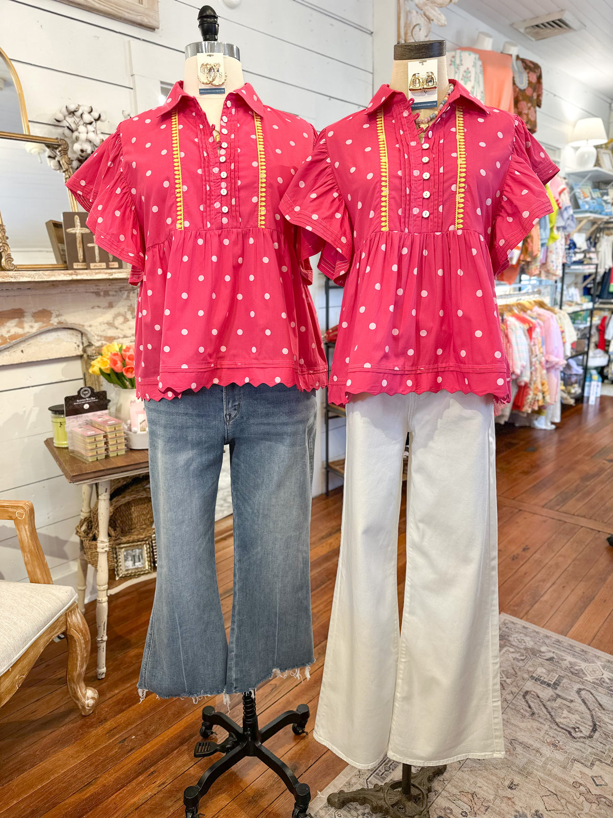 Two mannequins wearing pink polka dot shirts and jeans in a store setting.