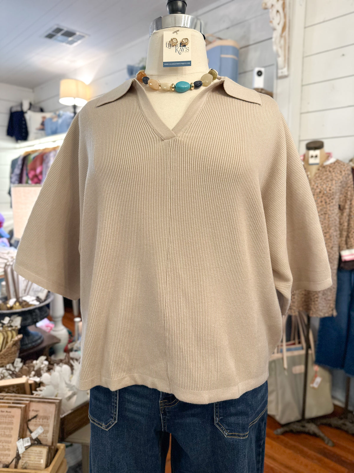 Sand color ribbed 3 quarter sleeve sweater top with collar inside store setting 
