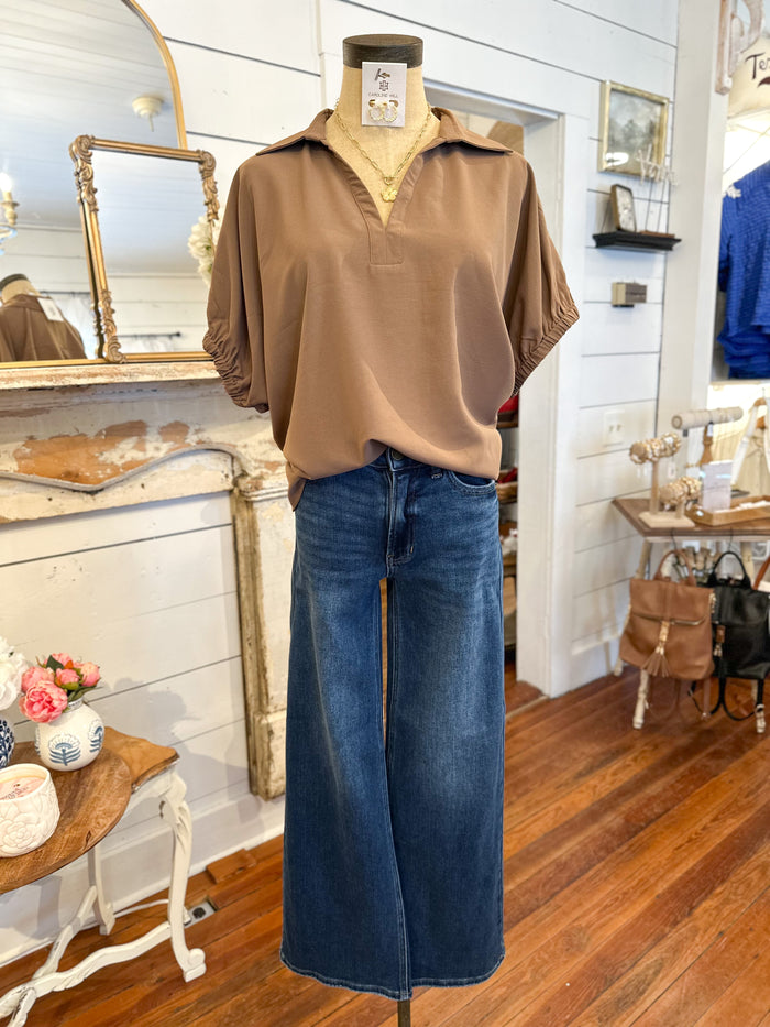 Mannequin wearing a brown shirt and blue jeans in a store setting