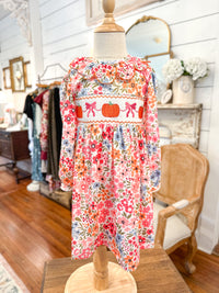 Floral dress on a mannequin in a store setting with mirrors and clothing racks. toddler pumpkin dress 