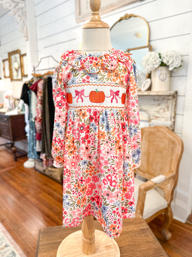 Floral dress on a mannequin in a store setting with mirrors and clothing racks. toddler pumpkin dress 