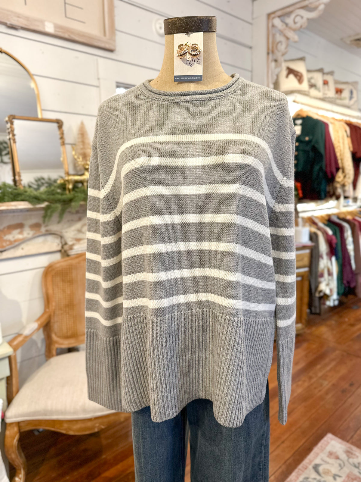 Gray and white striped sweater on a mannequin in a store setting