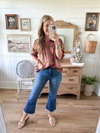 Woman taking a mirror selfie in a room with wooden floor and furniture. magenta pink and green design. 