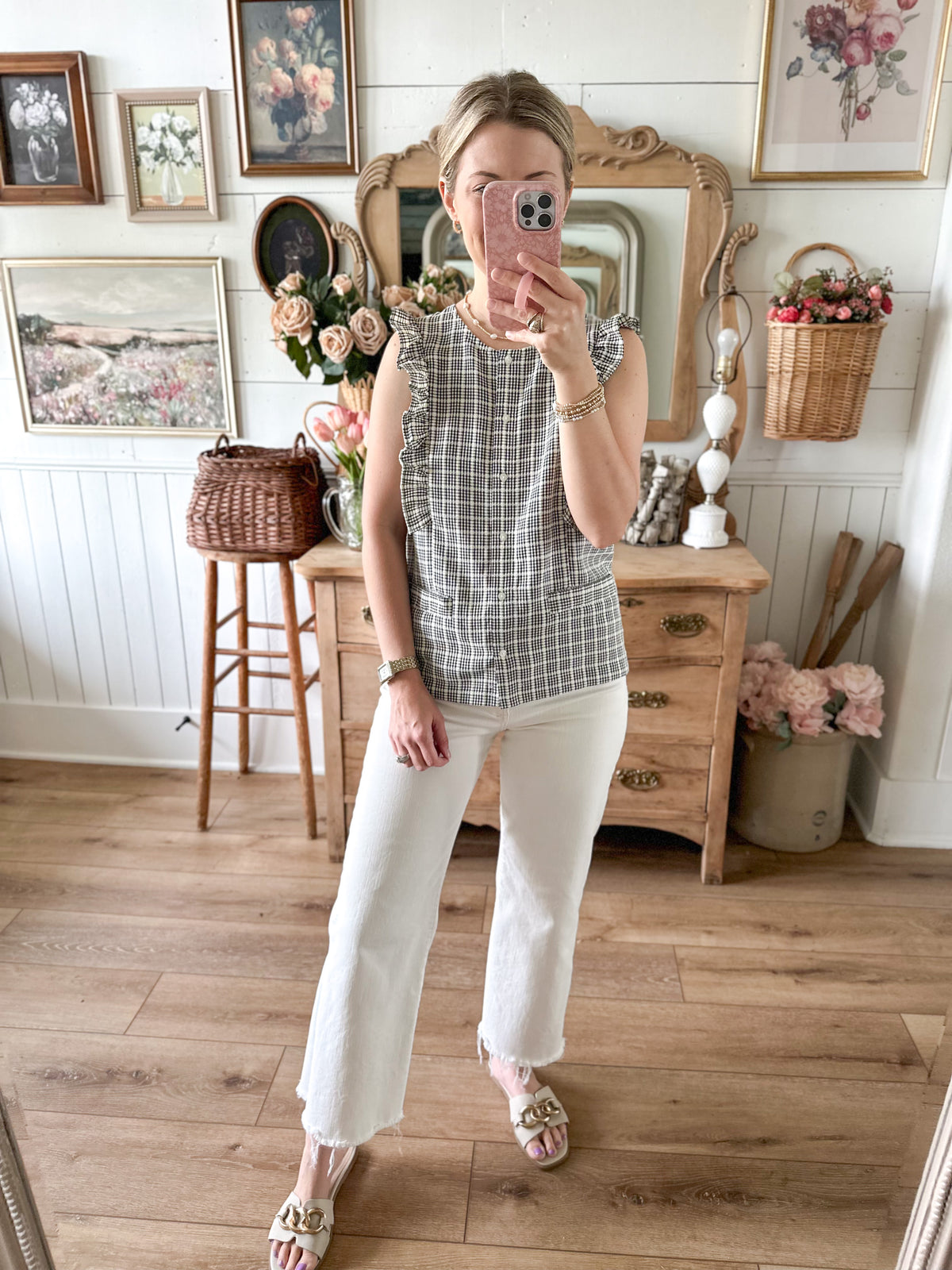 Woman taking a mirror selfie in a room with wooden floor and decor.
Cream and black button down blouse 