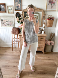 Woman taking a mirror selfie in a room with wooden floor and decor.
Cream and black button down blouse 