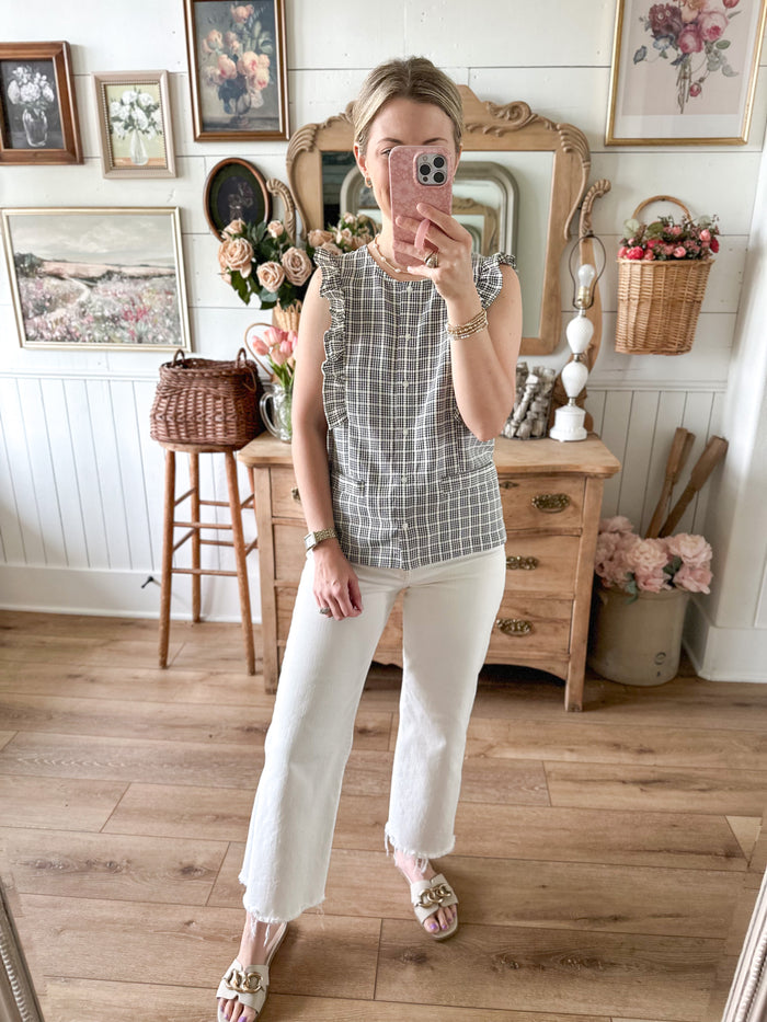 Woman taking a mirror selfie in a room with wooden floor and decor.
Cream and black button down blouse 