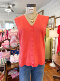Mannequin wearing a coral sleeveless button-up top and blue jeans in a store setting.