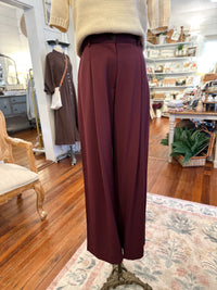 Maroon pants on a mannequin in a store setting with wooden floors and shelves.