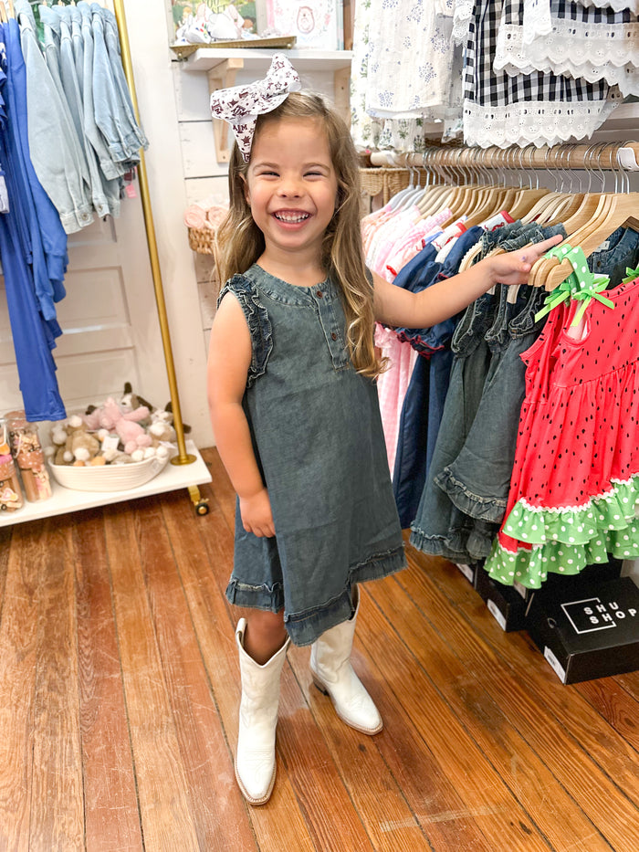 Little girl wearing dark wash denim dress with white boots 