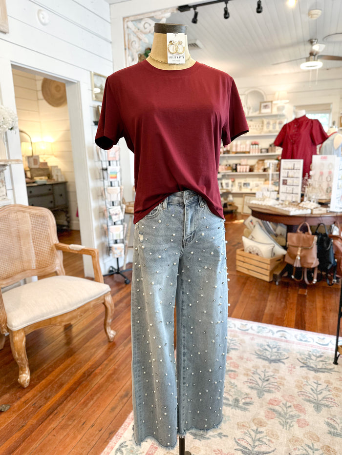 Mannequin wearing a burgundy shirt and light blue pearl  jeans in a store setting